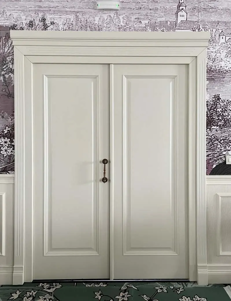 Installed white double door with a decorative top cornice