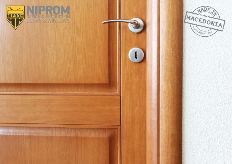 Close-up of a cherry-tone door with a raised panel and chrome lever