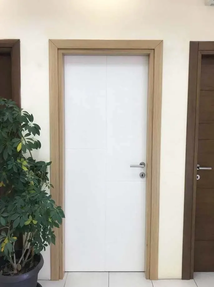 Installed white door with offset vertical and horizontal grooves in an oak-tone frame