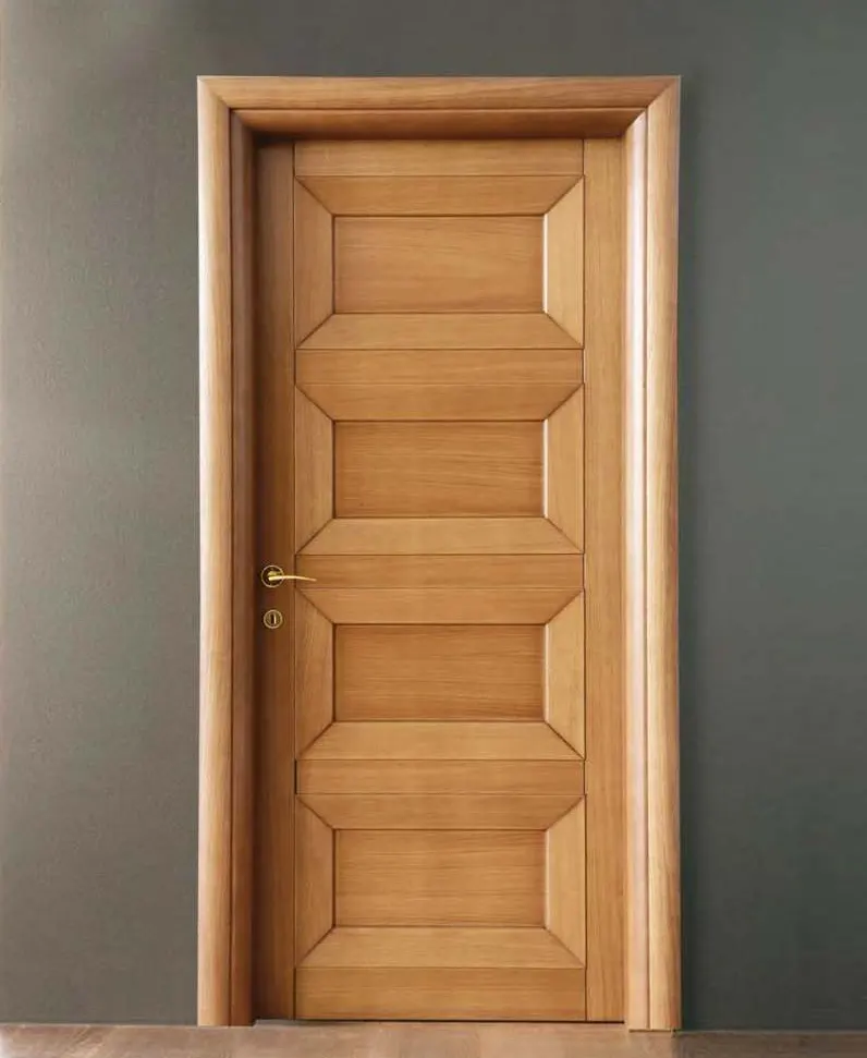 Honey-tone four-panel solid wood door with a brass handle against a grey wall