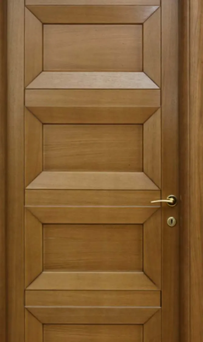 Close-up of a golden-brown solid wood door: bevelled panels and brass lever handle with keyhole